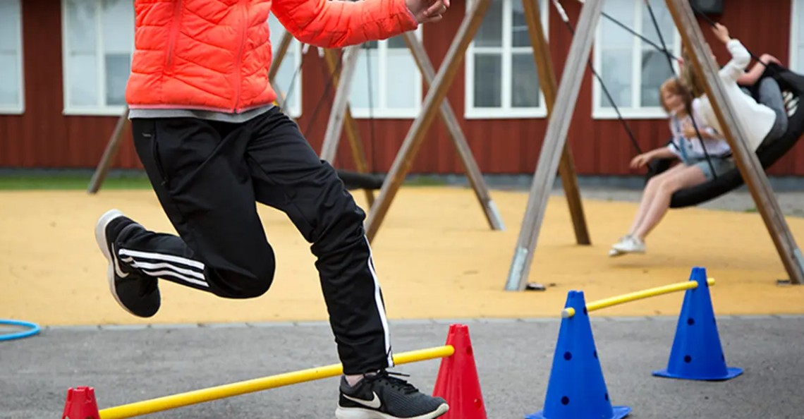 Person på skolgård och barn som gungar